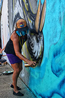 Beth Warmath painting a large blue mural